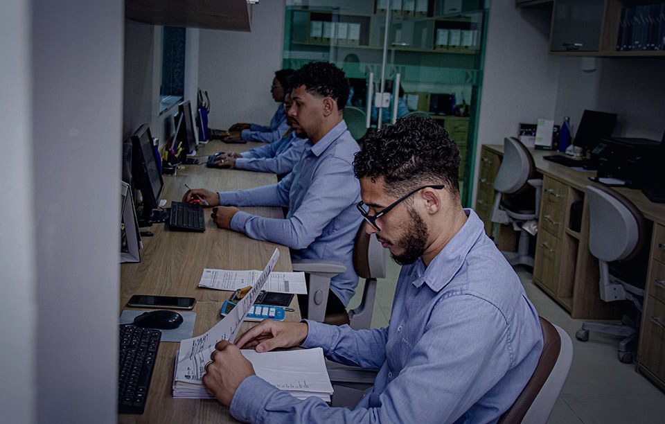Equipe da Kadoshi em rotina operacional no escritório, analisando documentos e sistemas